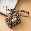 A leopard print PU leather mini wallet with a gold-toned chain attached, resting on a beige surface.