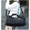 A black duffel bag with a shoe pocket is carried by a person wearing a white top.