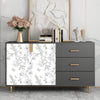 A gray cabinet with a white floral peel-and-stick wallpaper panel, flanked by a framed artwork and a vase of pink flowers.