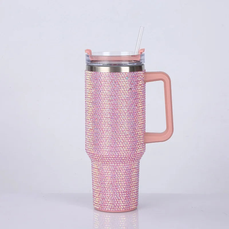 A pink rhinestone bling tumbler with a handle and straw is shown against a white background.
