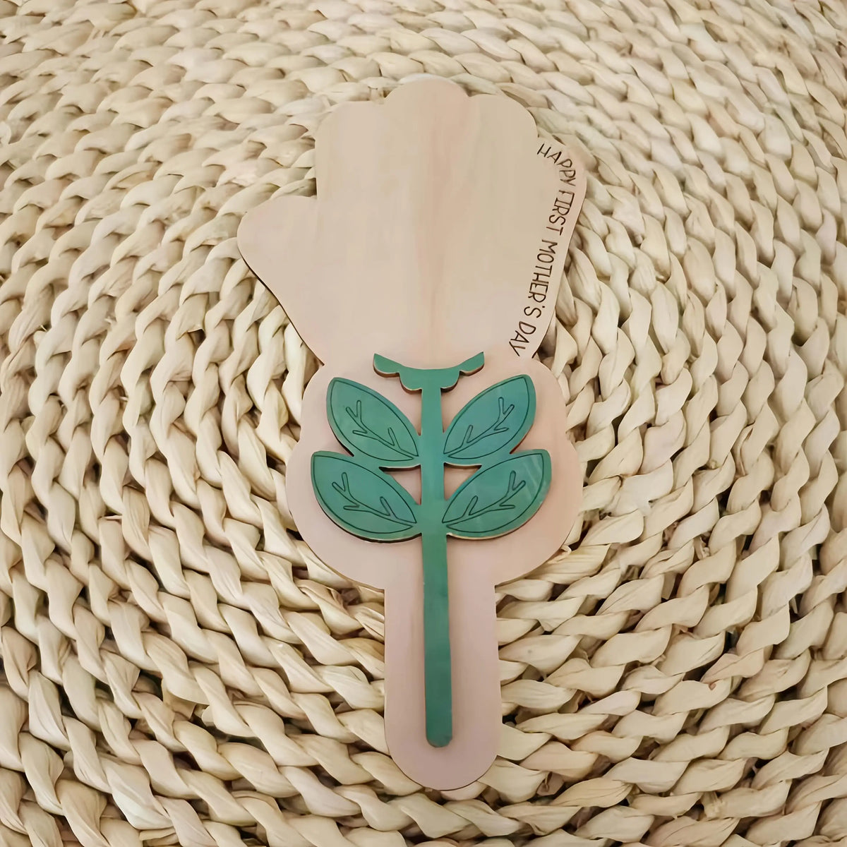 A wooden handprint keepsake plaque kit featuring a green leaf design on a light wood background.