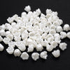 A pile of 100 white acrylic pearl spacer beads for jewelry making.