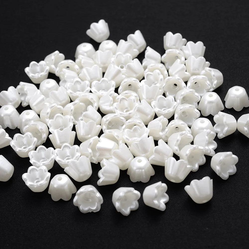 A pile of 100 white acrylic pearl spacer beads for jewelry making.