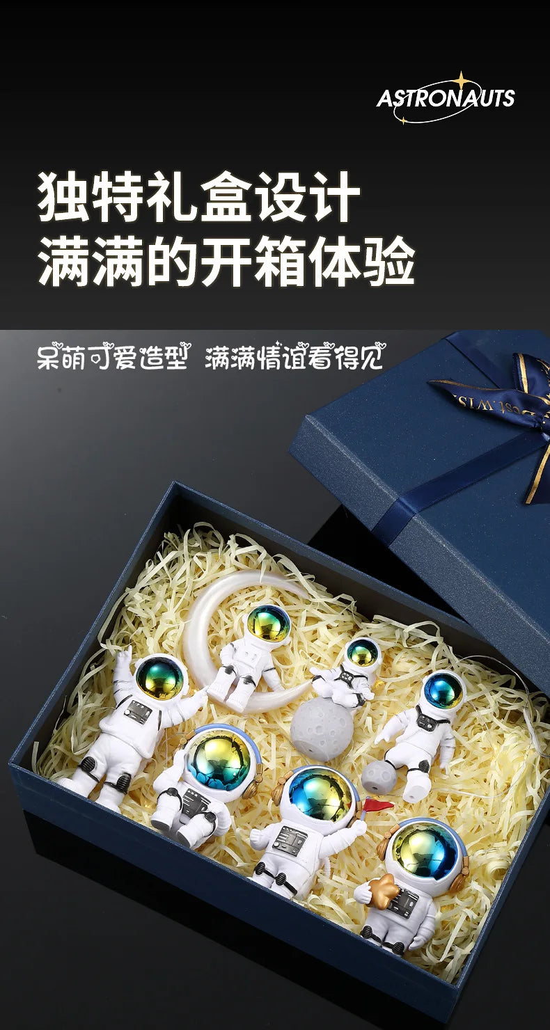 A set of handcrafted astronaut figurine resin spacemen displayed in a blue box with shredded yellow material.