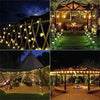 Outdoor fairy lights strung across a wooden fence and draped over a rustic outdoor dining area at night