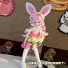 A pink-haired doll wearing a frilly pink dress and white stockings, with large bunny ears, displayed on a stand.