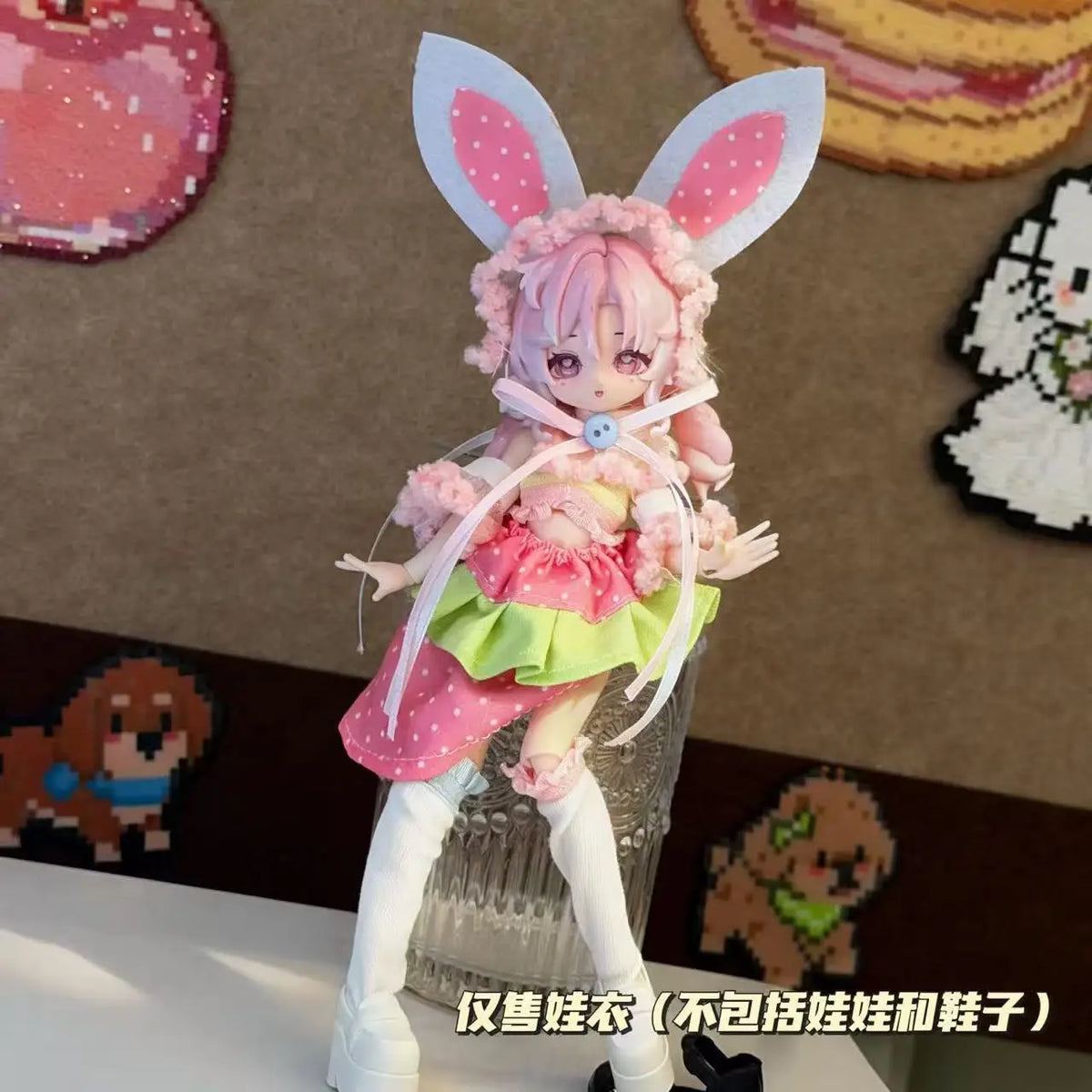 A pink-haired doll wearing a frilly pink dress and white stockings, with large bunny ears, displayed on a stand.