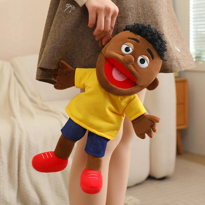 A soft plush full-body hand puppet of a Black child with dark curly hair wearing a yellow shirt and blue shorts.