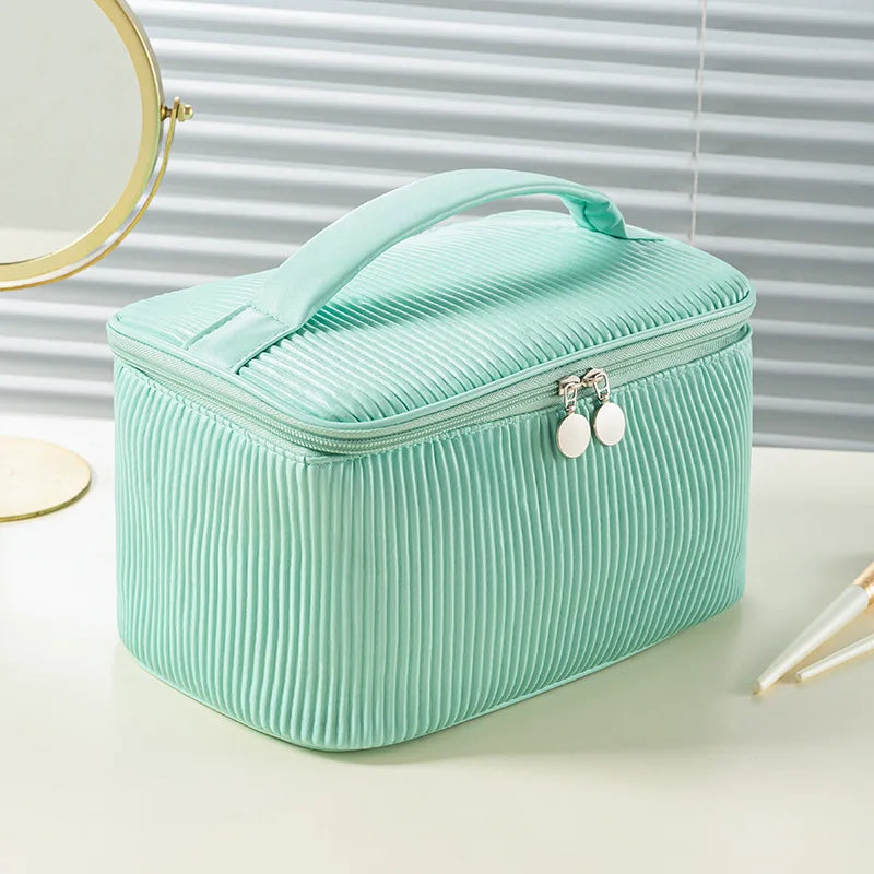 A mint green corrugated fabric makeup bag with a lid and a zipper, resting on a light surface.