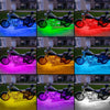 A collection of motorcycles illuminated by various colors of RGB LED strip lights.