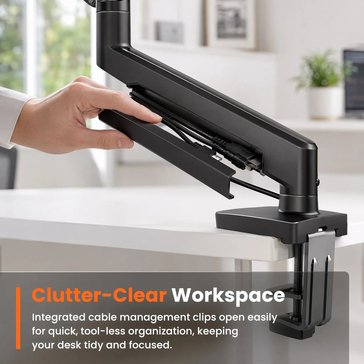 Une main ajuste un bras d'écran noir robuste avec des clips de gestion de câbles intégrés pour un espace de travail dégagé.