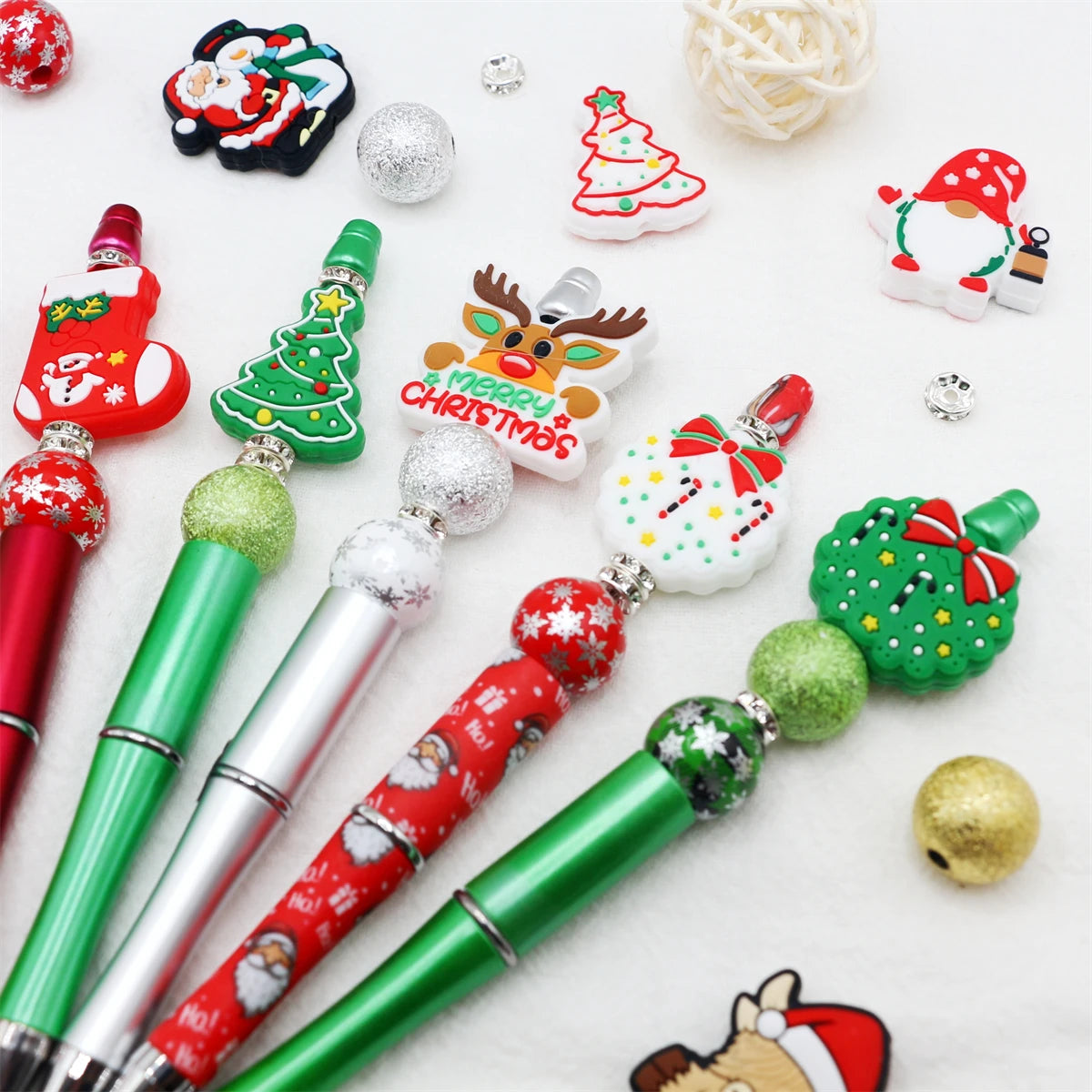 A craft kit featuring a beaded ballpoint pen and various Christmas-themed beads and ornaments.