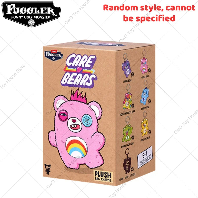 A pink Fuggler bear plush keychain with a rainbow detail is shown in its packaging box.