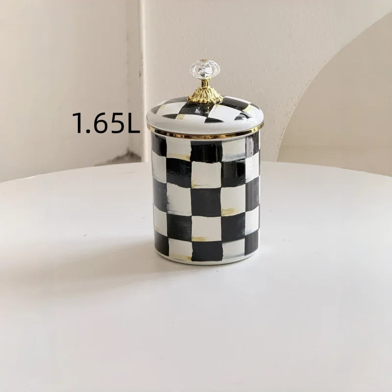 A white and black checkerboard porcelain storage jar with a gold lid sits on a white surface.