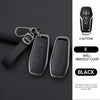 A black car key case cover with a bracelet clasp and four buttons shown next to a leather strap.