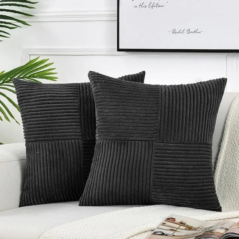 A set of two dark gray corduroy patchwork throw pillow covers displayed on a white sofa.