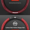 A close-up view of a red steering wheel cover with a carbon fiber pattern, featuring the Nissan logo and text.