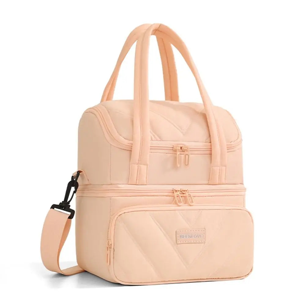 A light peach insulated leakproof reusable lunch bag with pink quilted texture and carrying handles.