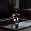 A metallic spinning top levitating above a laptop keyboard on a wooden desk.