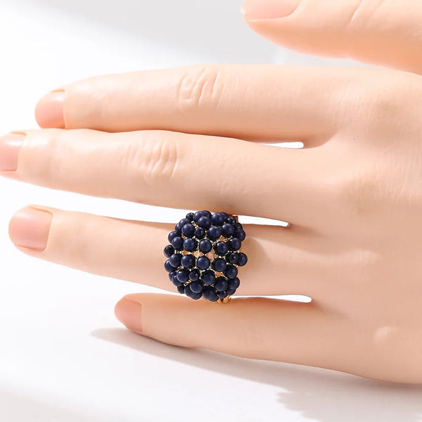 Eine Hand trägt einen Vintage-Goldsteinring mit kleinen dunkelblauen Perlen.