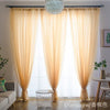 Light beige sheer voile curtains hanging in a window with a decorative sphere light fixture.