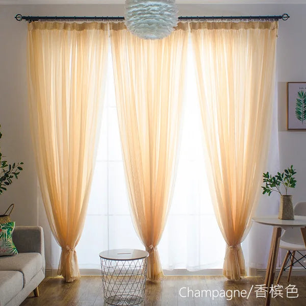 Light beige sheer voile curtains hanging in a window with a decorative sphere light fixture.