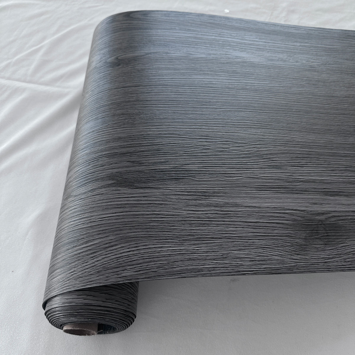 Roll of wood grain PVC self-adhesive decal showing dark gray texture and vertical lines