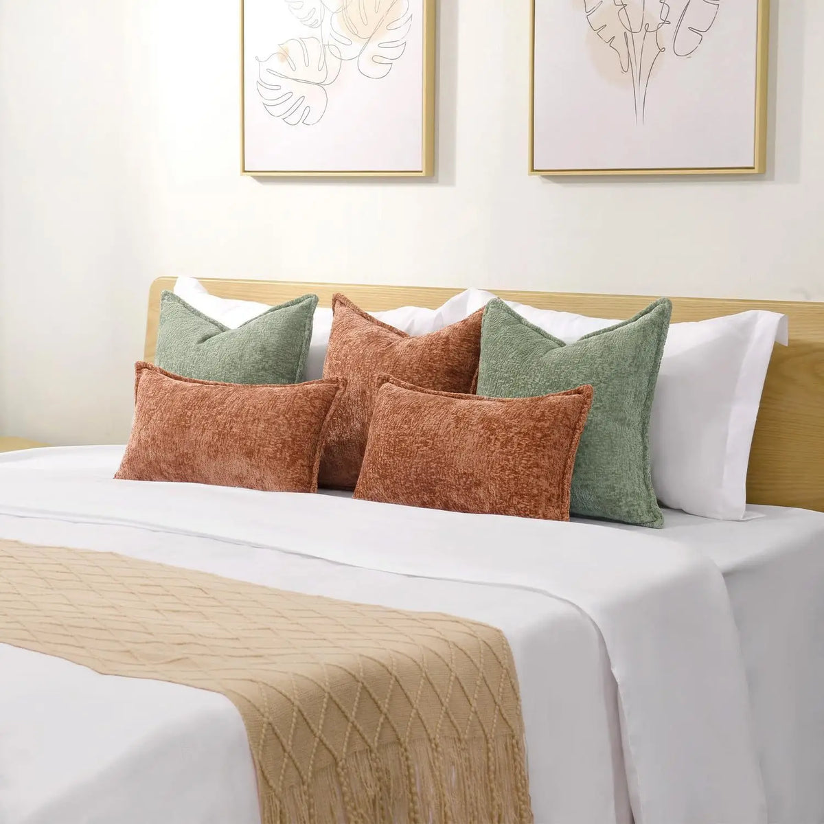 A collection of square decorative cushion covers in shades of green, brown, and white on a bed