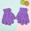 A pair of purple plush winter gloves for kids resting on a light pink and mint green background with a lime slice.