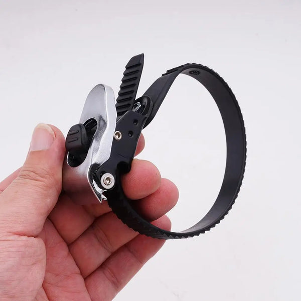 A hand holds a heavy-duty ratchet strap with a metal buckle and teeth.
