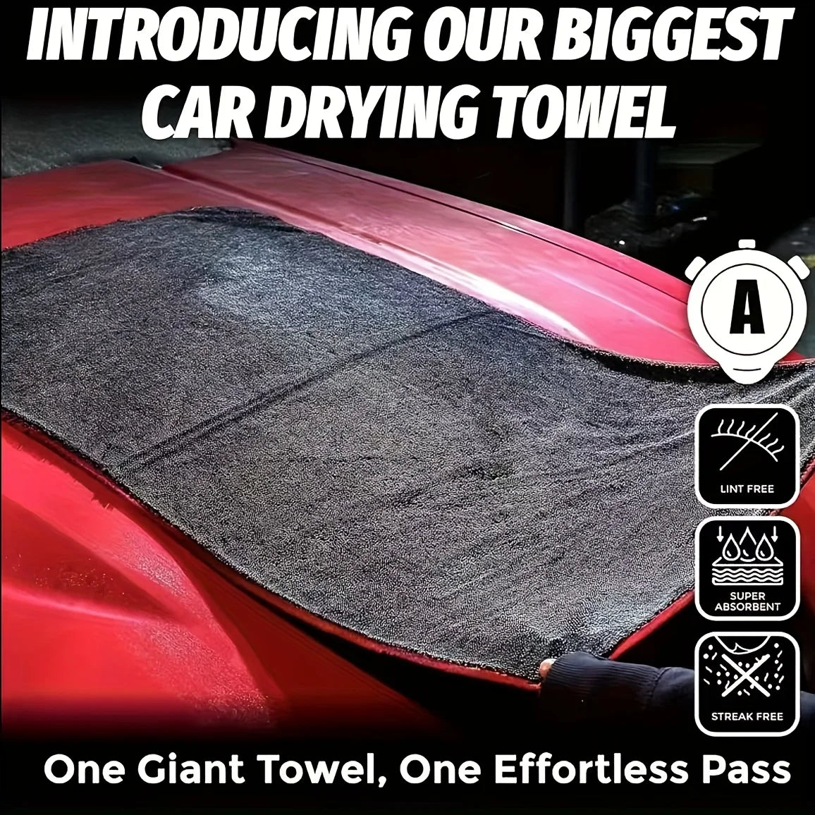 A close-up of a large black microfiber car drying towel being used on a red car surface.