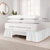 White bed skirt with elegant ruffles and elastic wrap-around strap shown on a bed.