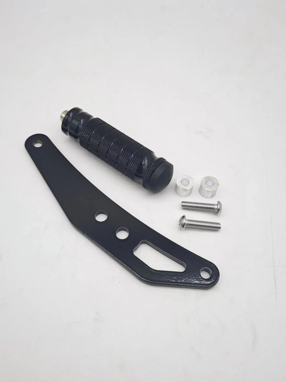A set of black CNC aluminum foot pegs, a black grip, and mounting hardware for electric dirt bikes.