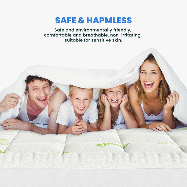 Une famille de quatre souriante allongée sur un matelas de surmatelas en viscose de bambou blanc.