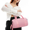 A woman holds a pink compact nylon gym bag with an adjustable strap.