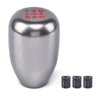A silver aluminum gear shift knob with markings and three accompanying adapters.