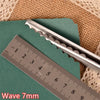 Silver pinking shears shown next to a ruler on a green surface.