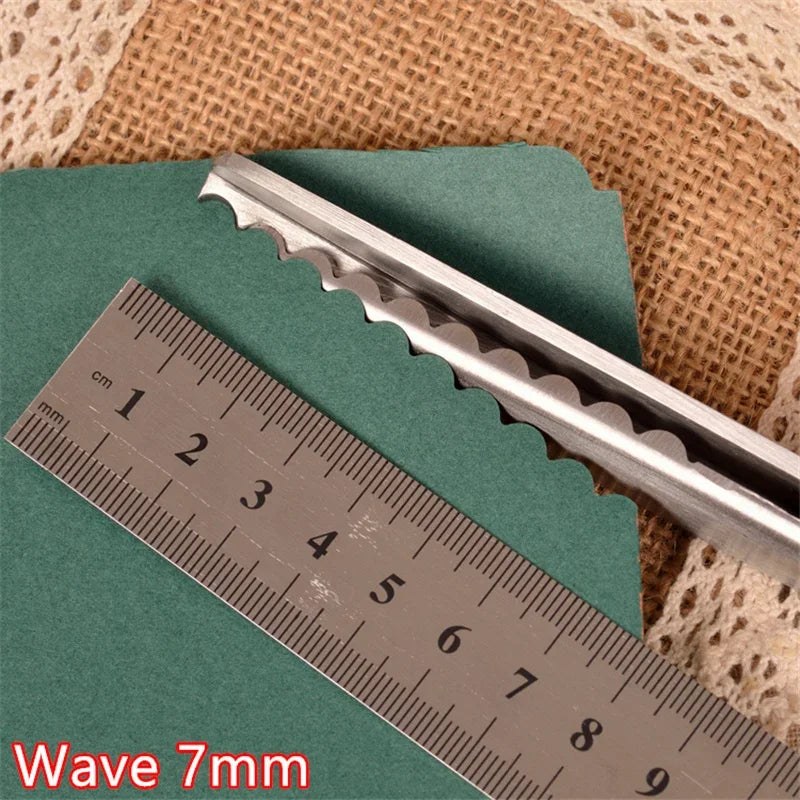 Silver pinking shears shown next to a ruler on a green surface.
