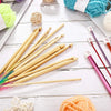 A collection of 23 bamboo crochet hooks and yarn is displayed on a white wooden surface.