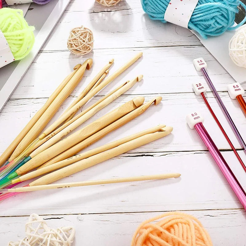 A collection of 23 bamboo crochet hooks and yarn is displayed on a white wooden surface.