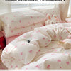A set of pink and white bedding including a duvet cover and two pillowcases with tiny pink bow prints.