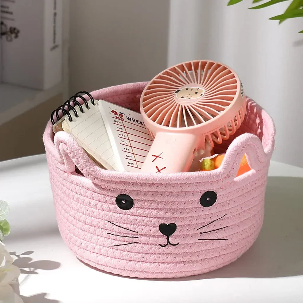 Pink woven cotton rope storage basket with a fan inside, shaped like a cat's face.