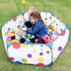 A colorful foldable kids ball pit play tent filled with plastic balls on a green lawn.