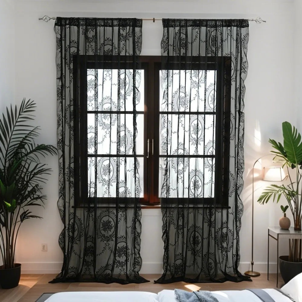 Black ruffled lace sheer curtains with floral embroidery covering a window in a bedroom setting