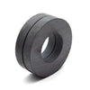 A close-up view of a dark gray industrial ceramic ring magnet with a smooth, cylindrical shape.
