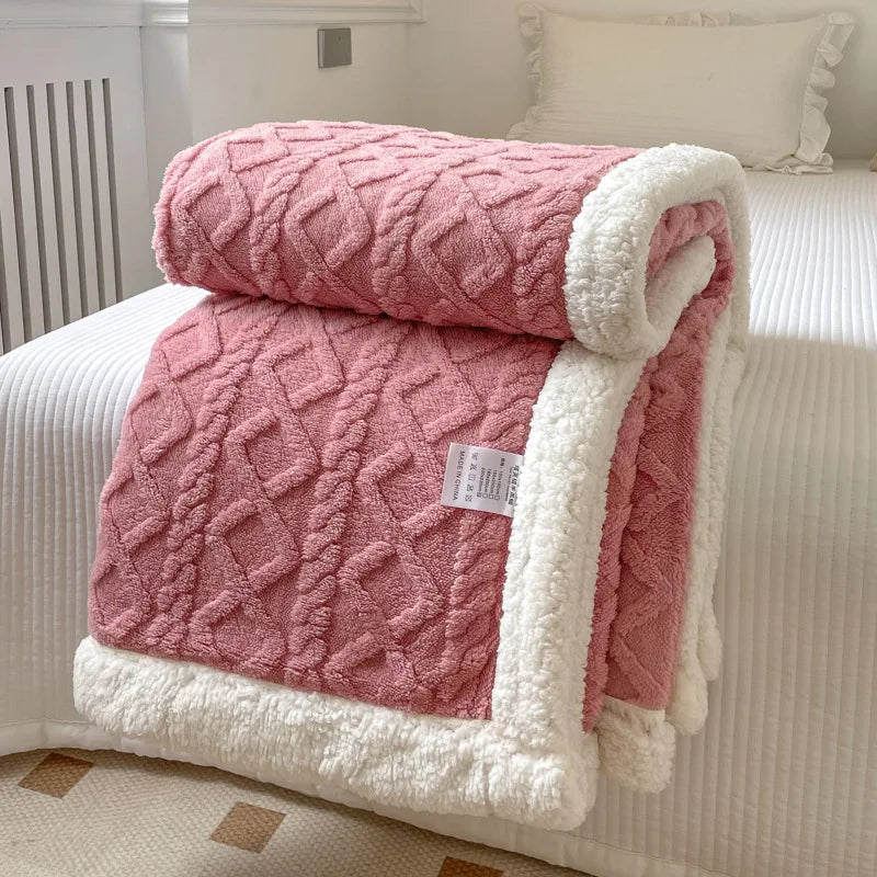 A pink and white double-layer fleece throw blanket folded on a bed