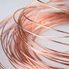 A close-up of multiple strands of rose gold copper wire coiled and arranged in a circular pattern.