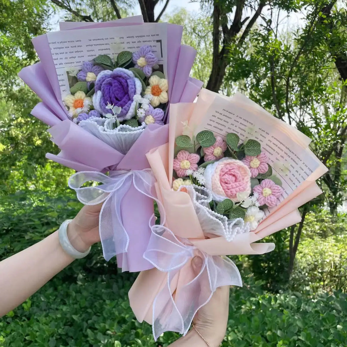 Handgefertierter Blumenstrauß aus Häkelwerk mit lila und rosa Blumen, umwickelt in durchscheinendem Lilapapier.