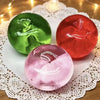 Three fruit-shaped slow-rising squeeze toys in green, red, and pink resting on white lace