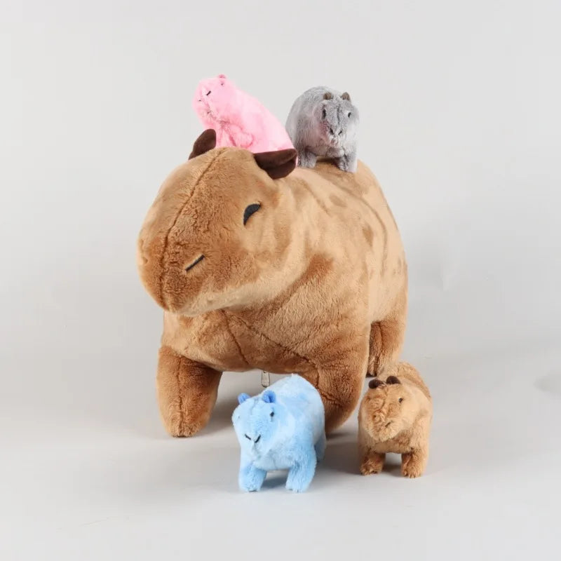A brown stuffed animal resembling a capybara is sitting with a pink and gray simulation capybara and a small blue stuffed ani